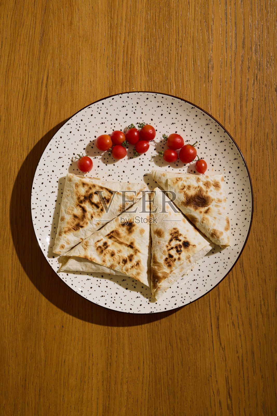 美味诱人的扁面包，上面放着樱桃番茄，摆放在木桌上。照片摄影图片