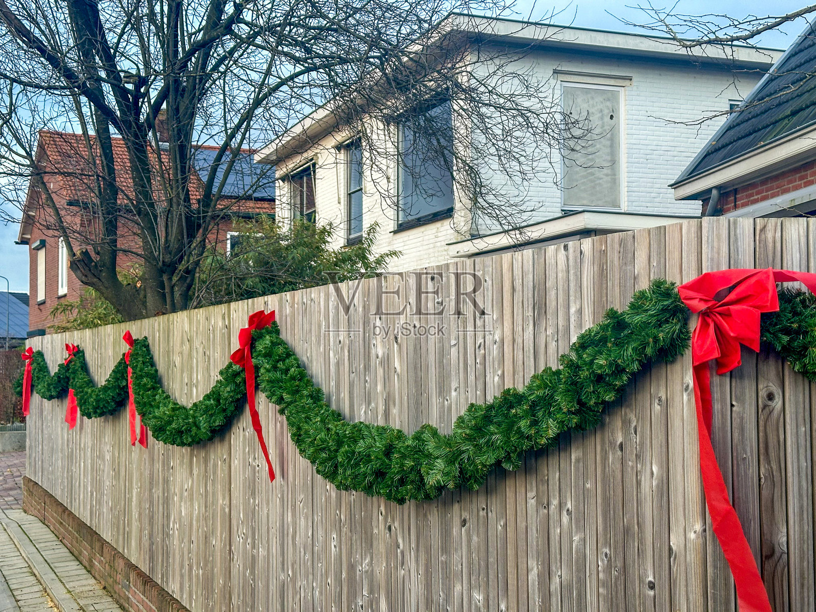 绿色花环上挂着红色蝴蝶结的围栏照片摄影图片
