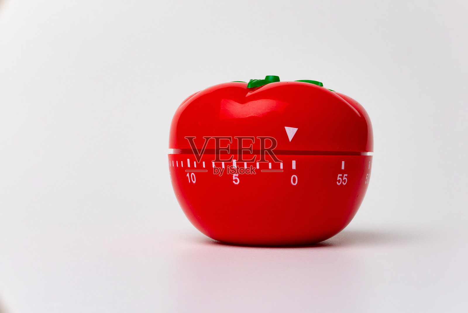 机械番茄形厨房计时器的特写，用于烹饪和学习。用于番茄工作法进行时间和生产力管理。背景为白色，设置为5分钟。照片摄影图片