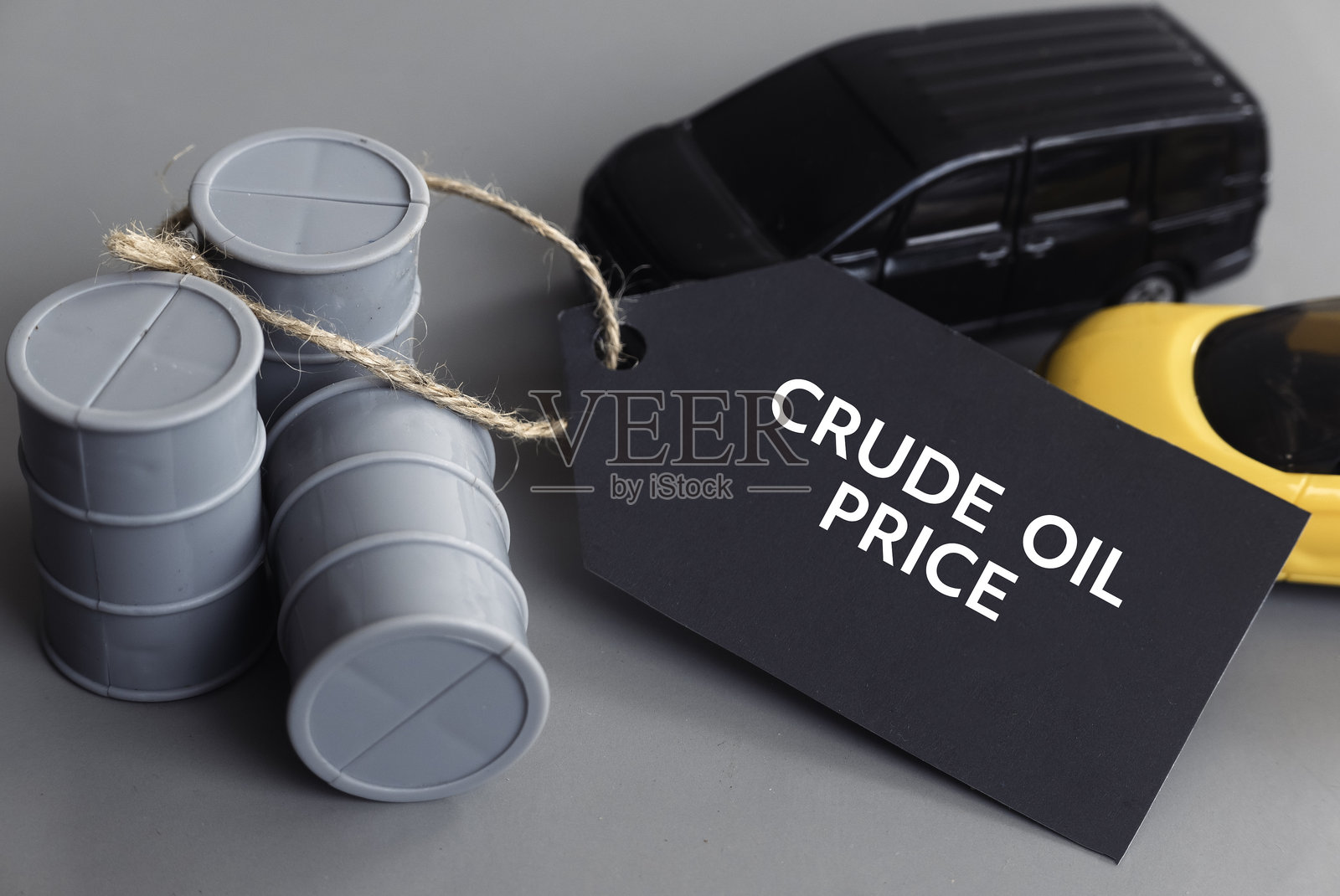 原油价格概念，背景为灰色，油桶和玩具车。照片摄影图片