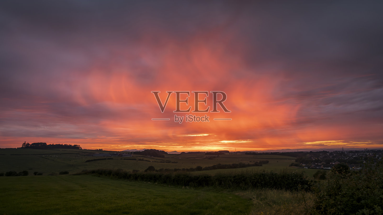戏剧性的日落映照在农田上，远处是阿伦岛的戈特费尔山。照片摄影图片