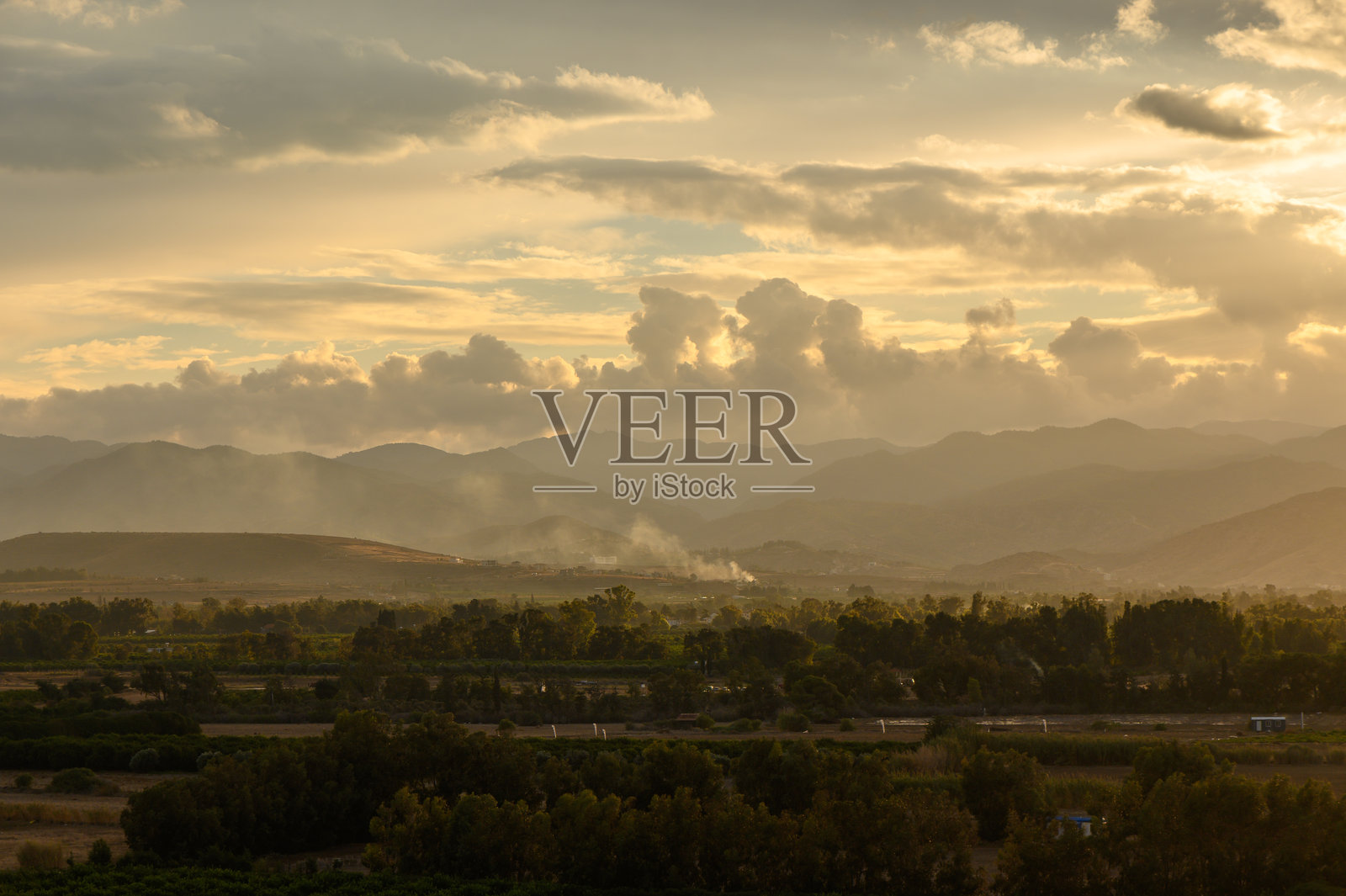 壮丽的日落为起伏的山丘和宁静的风景披上金色的光辉。照片摄影图片