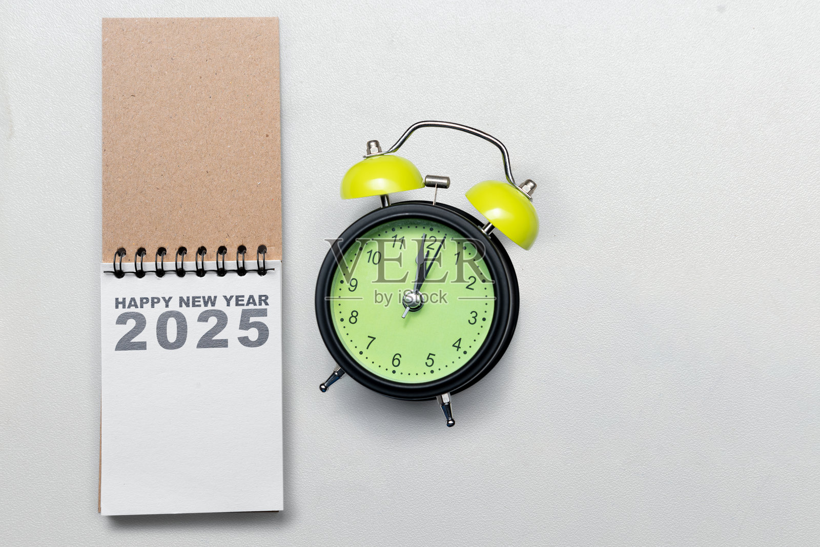 带有“2025新年快乐”文字的日历或记事本和一个闹钟，背景为白色。照片摄影图片