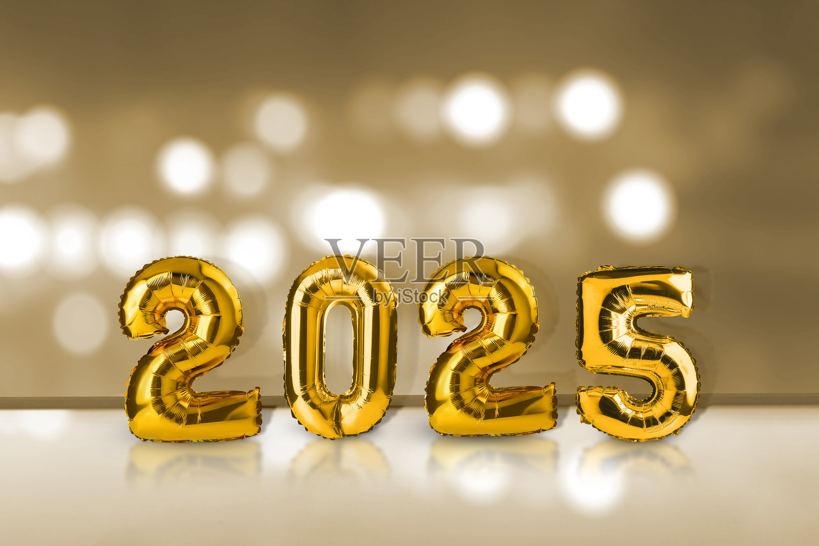 桌子上有金色氦气球，上面写着数字2025，背景是抽象的散景灯光。照片摄影图片