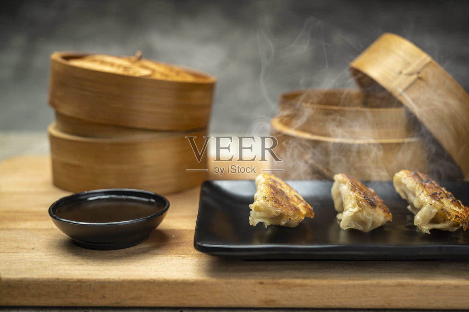 盘子里放着炸中式点心饺子、锅贴、饺子或饺子，桌上有酱油。适合早餐、午餐或晚餐的美食。照片摄影图片