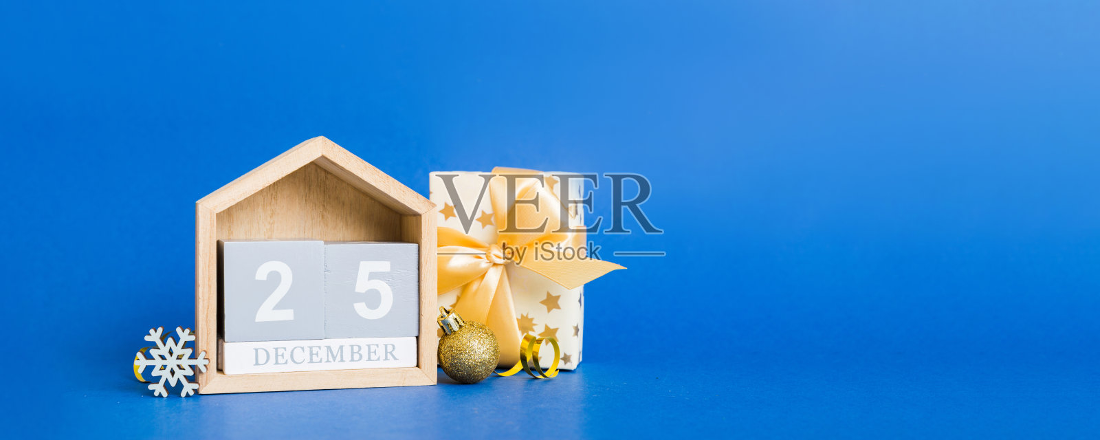 12月25日。彩色背景上的圣诞节组合，包含一个木制日历、一个礼品盒、玩具和装饰球，留有空白空间。照片摄影图片