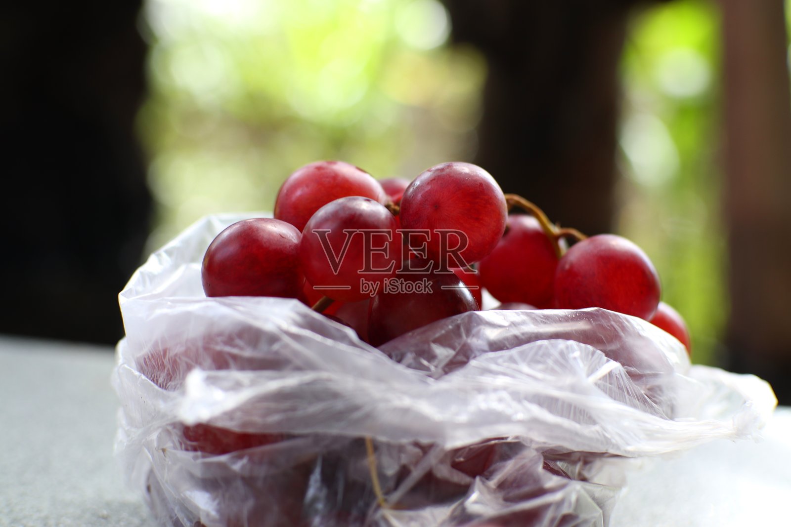 一个塑料袋里装满了红葡萄。照片摄影图片