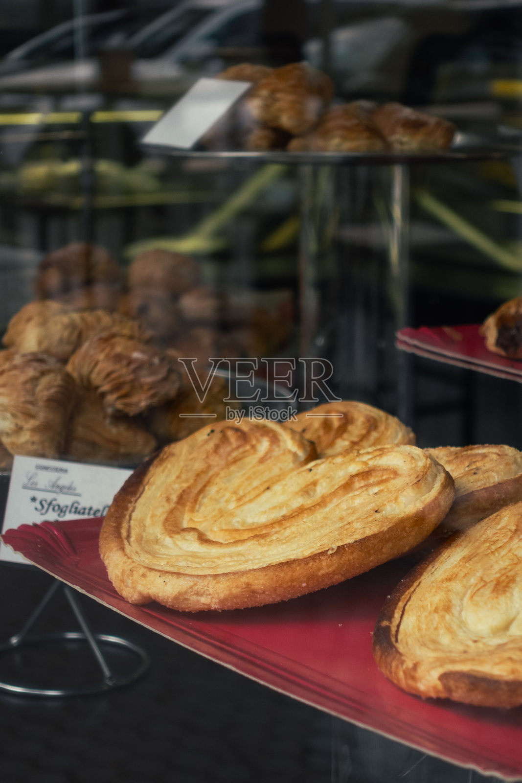 酥皮点心和糕点在面包店的橱窗展示中。照片摄影图片