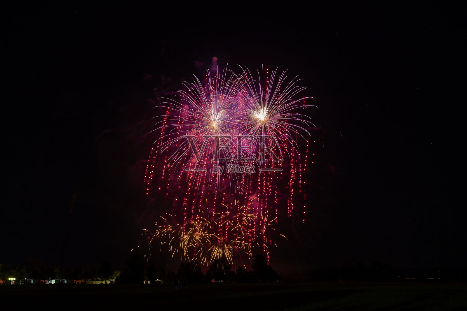 烟花在夜空中绽放，明亮的红色和金色火花照亮黑暗，营造出令人惊叹的新年庆祝视觉盛宴。照片摄影图片
