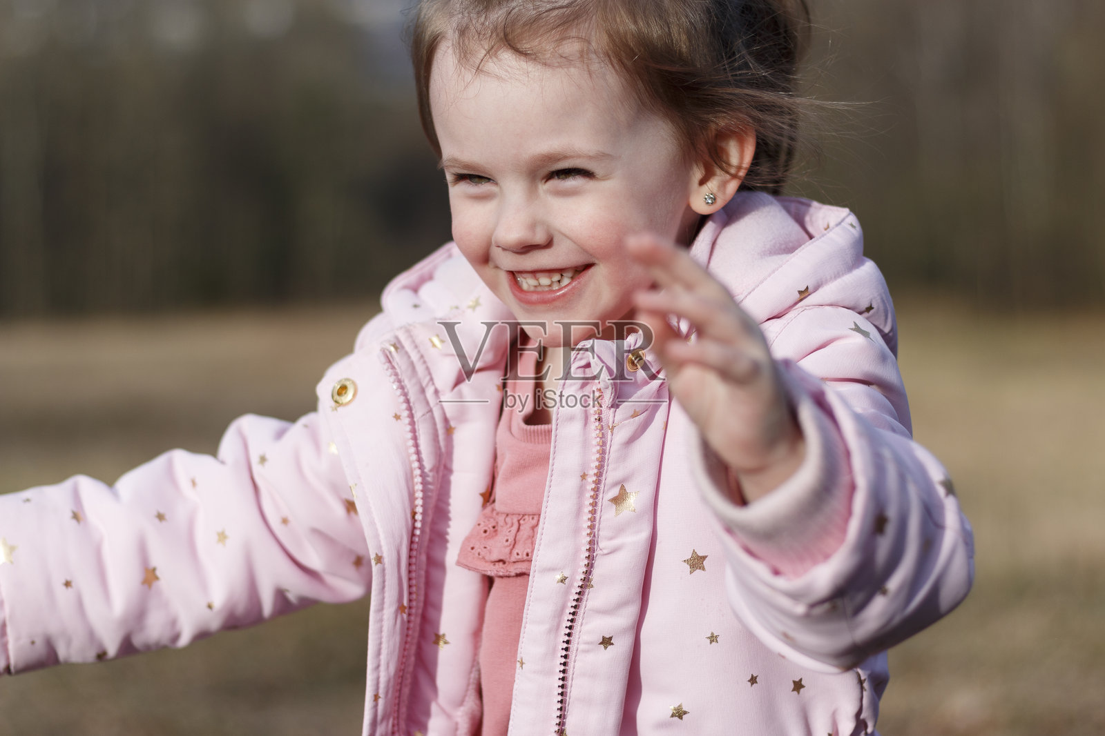 穿着粉色夹克的小女孩在冬季公园里玩泡泡，乐趣无穷。照片摄影图片
