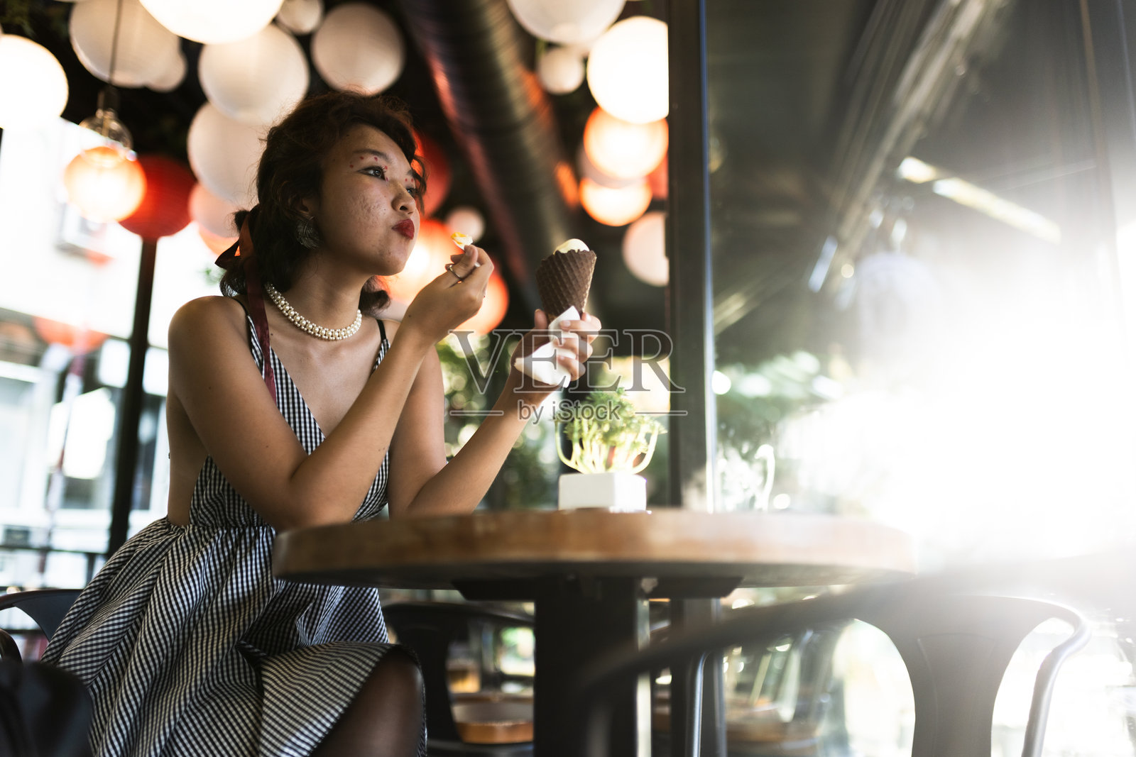 年轻女性在时尚咖啡馆享受冰淇淋，咖啡馆内装饰现代，氛围灯光柔和。照片摄影图片