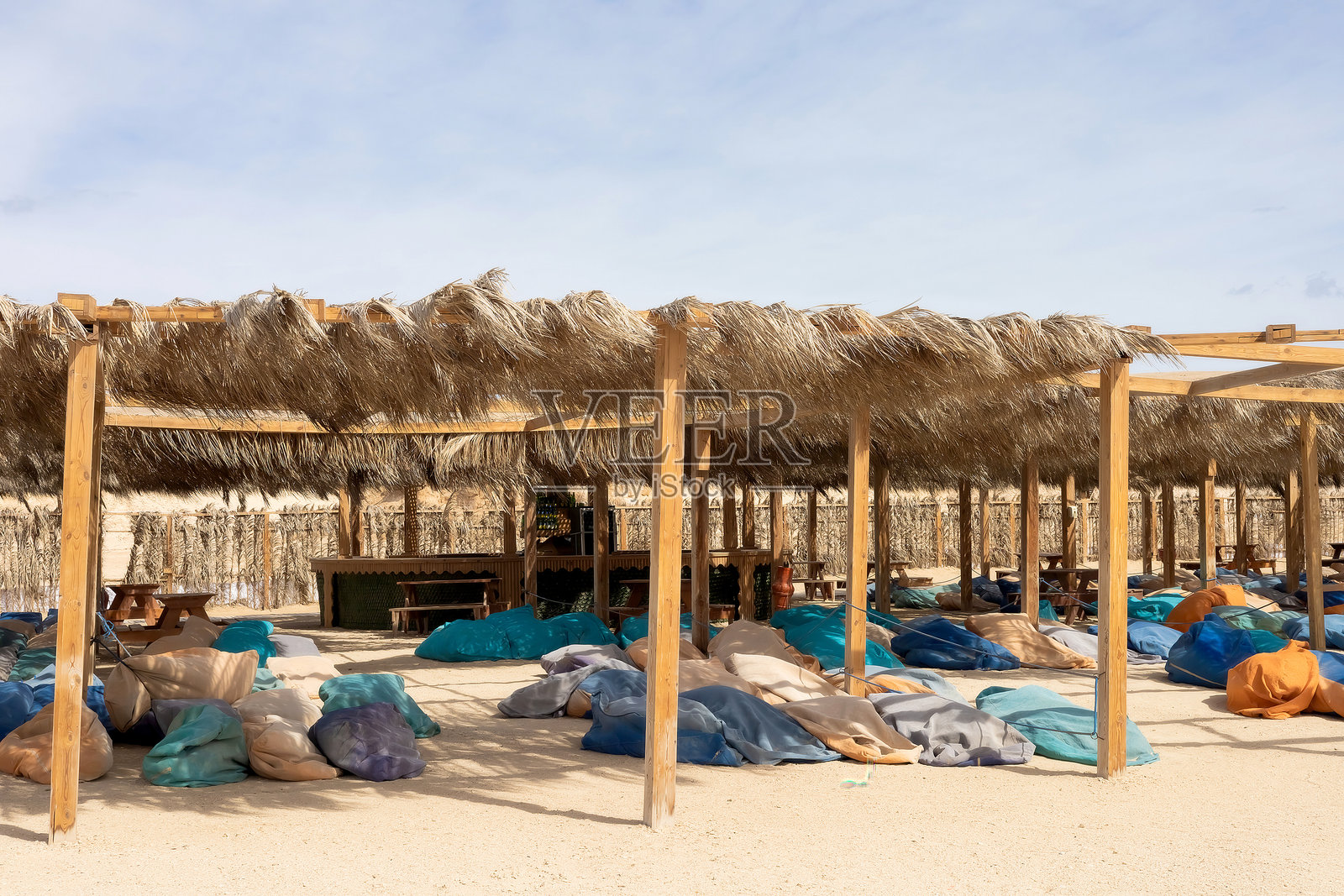 宁静的海滩绿洲，配有草棚和五彩缤纷的豆袋供放松使用照片摄影图片