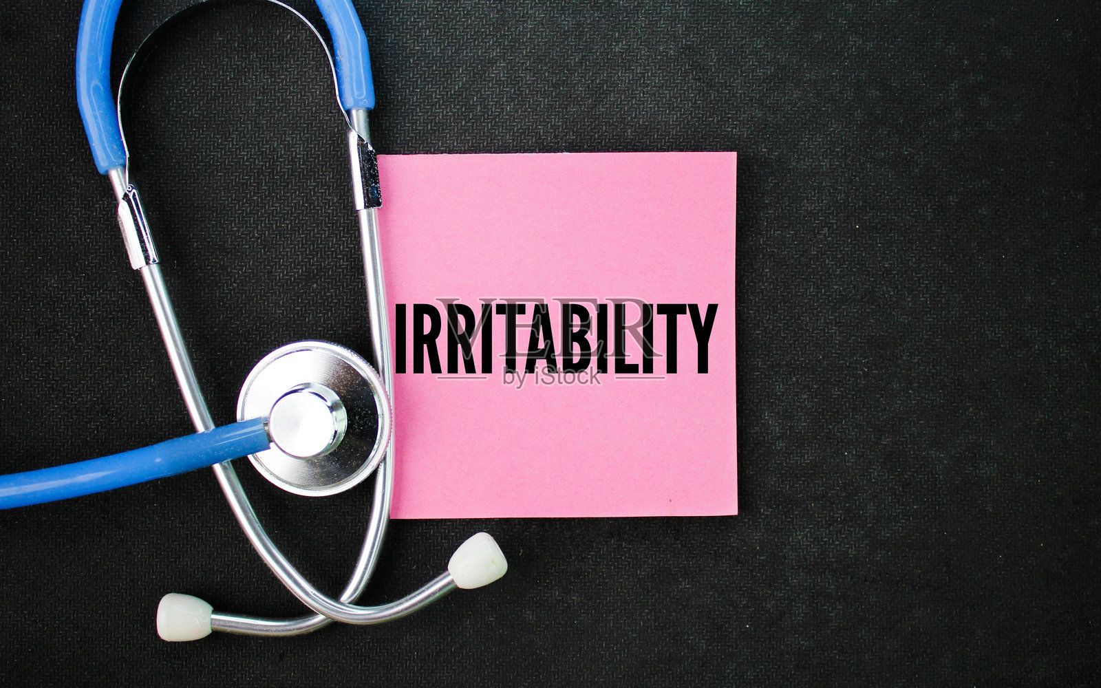 听诊器和写有“易怒”一词的粉色纸张。用来描述愤怒、烦躁和不耐烦的情绪。照片摄影图片