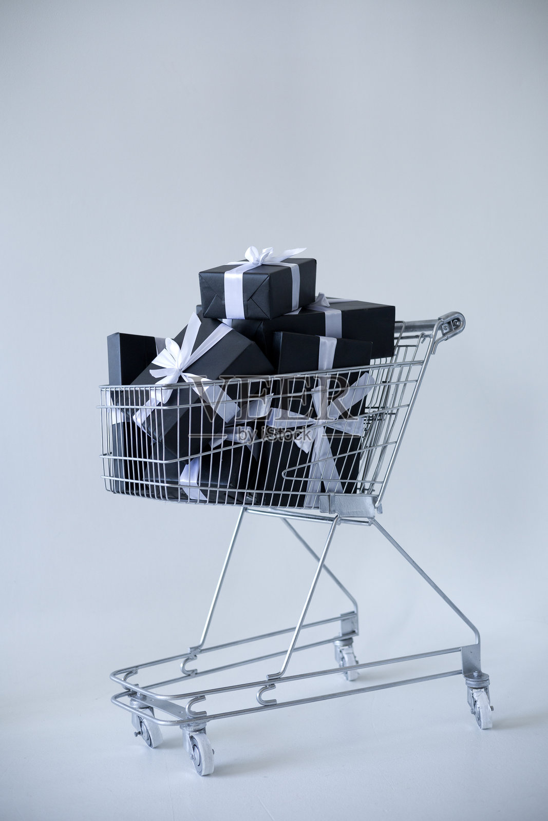 装满各种礼物的购物车，礼物用纸和丝带包装，背景为干净的白色。照片摄影图片