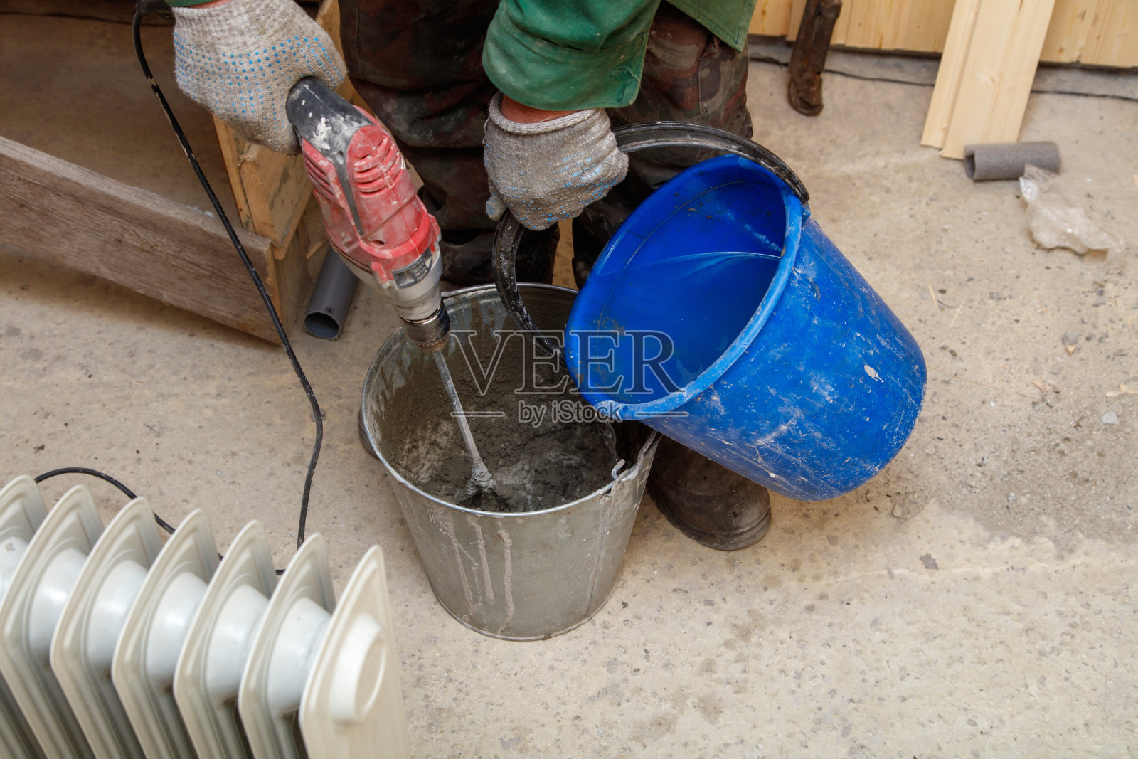 一个男人正在用锤子和桶混合水泥照片摄影图片