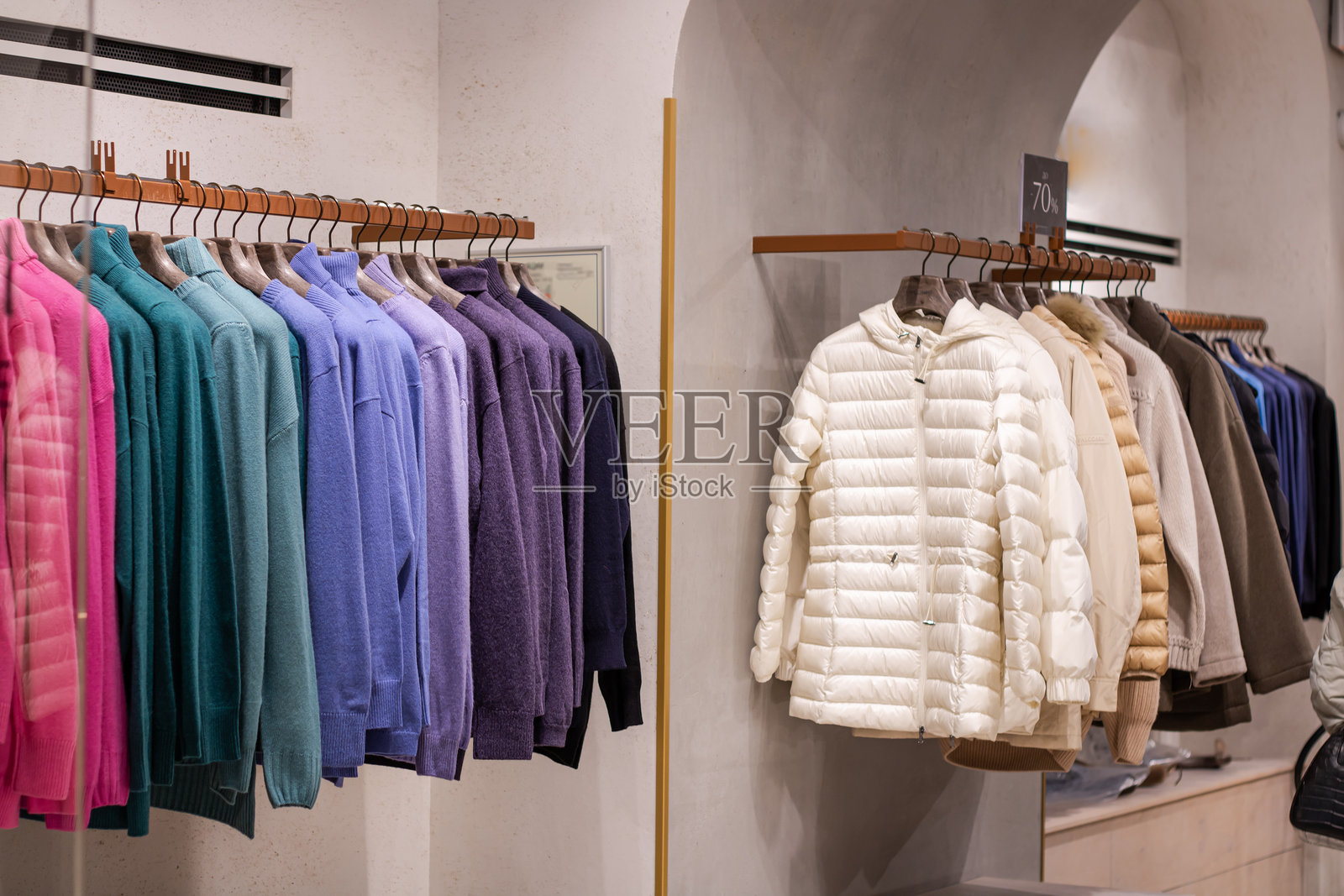 时尚的衣服挂在衣架上。商店中五颜六色的时尚男女服装的特写，包括短裤和毛衣。照片摄影图片