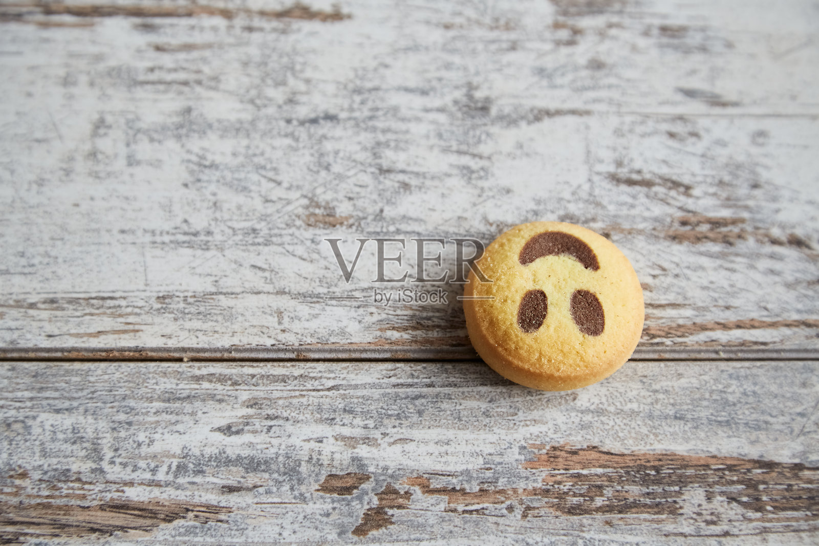 一个微笑饼干倒着躺在桌子上，特写，悲伤和坏心情，失望和忧伤。照片摄影图片