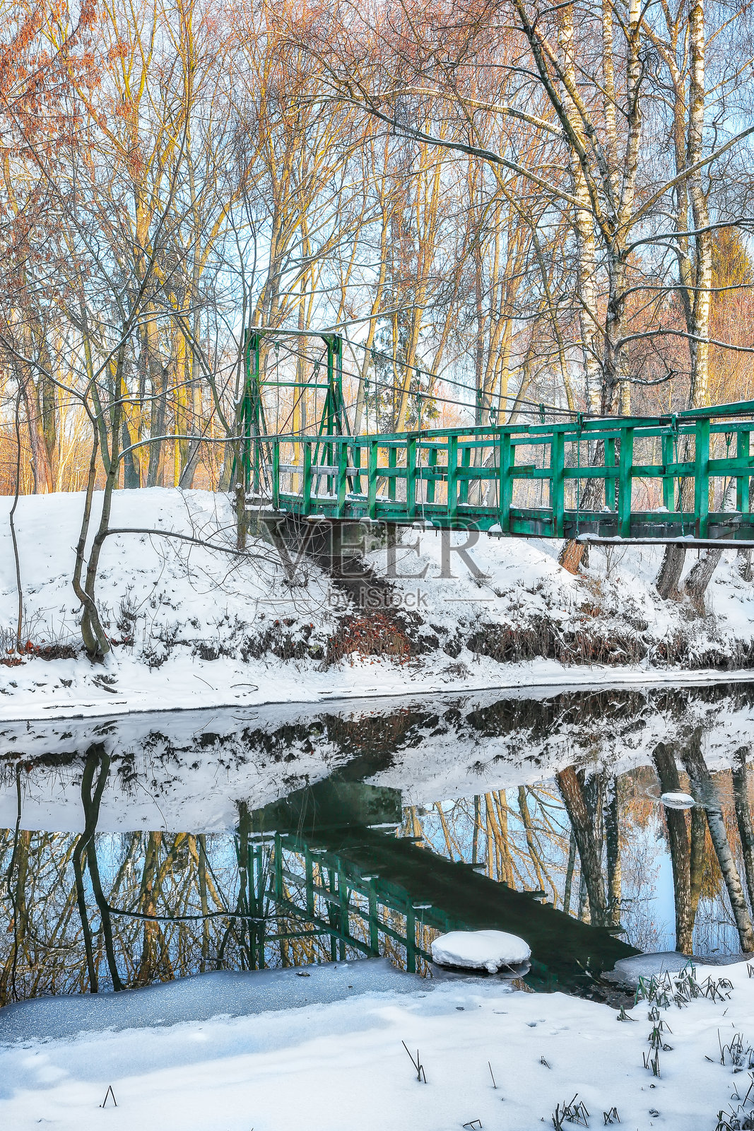 城市公园中壮观的风景，雪-covered树木和冰冻河面上的美丽倒影。照片摄影图片