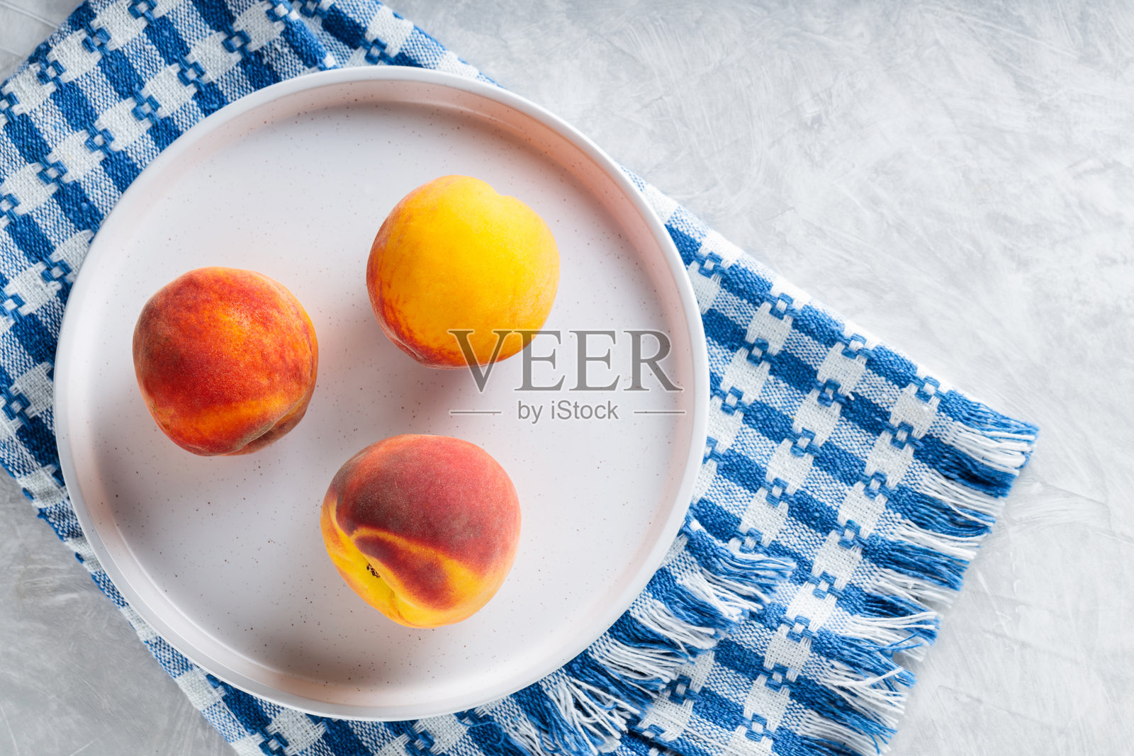 白盘上的成熟桃子与蓝白色亚麻餐巾照片摄影图片