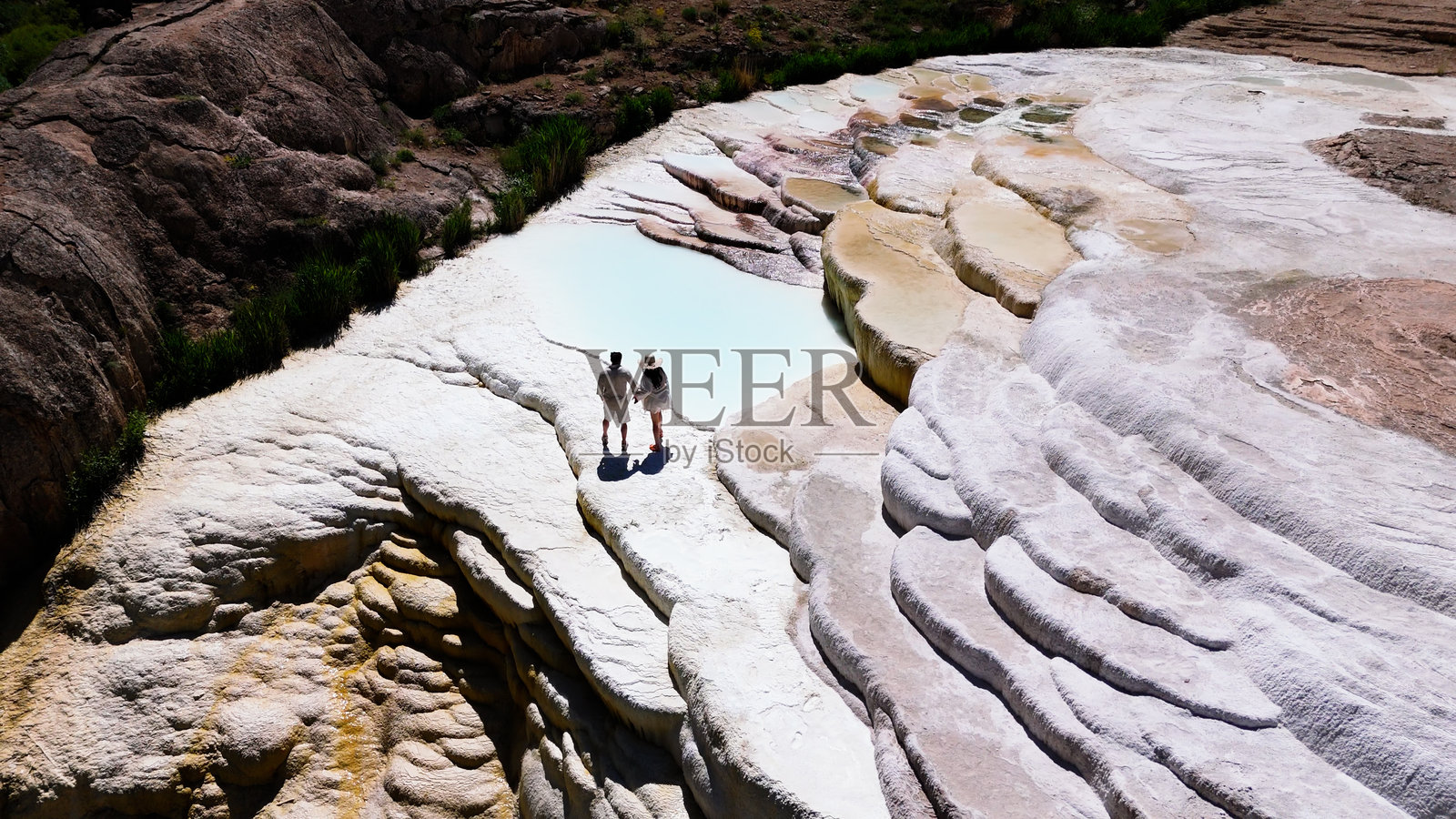 情侣在阳光明媚的日子里欣赏巴斯卡莱的石灰华。照片摄影图片