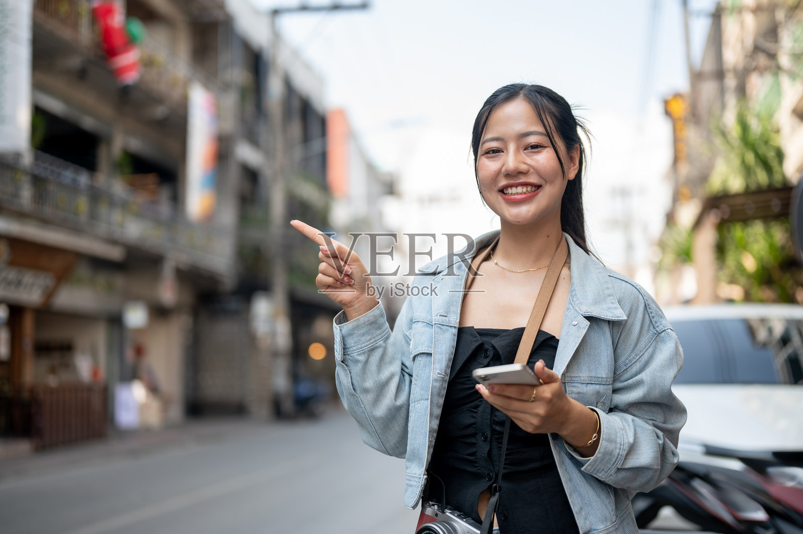 一位女性游客站在街边，指着天空，似乎在推荐某样东西。照片摄影图片