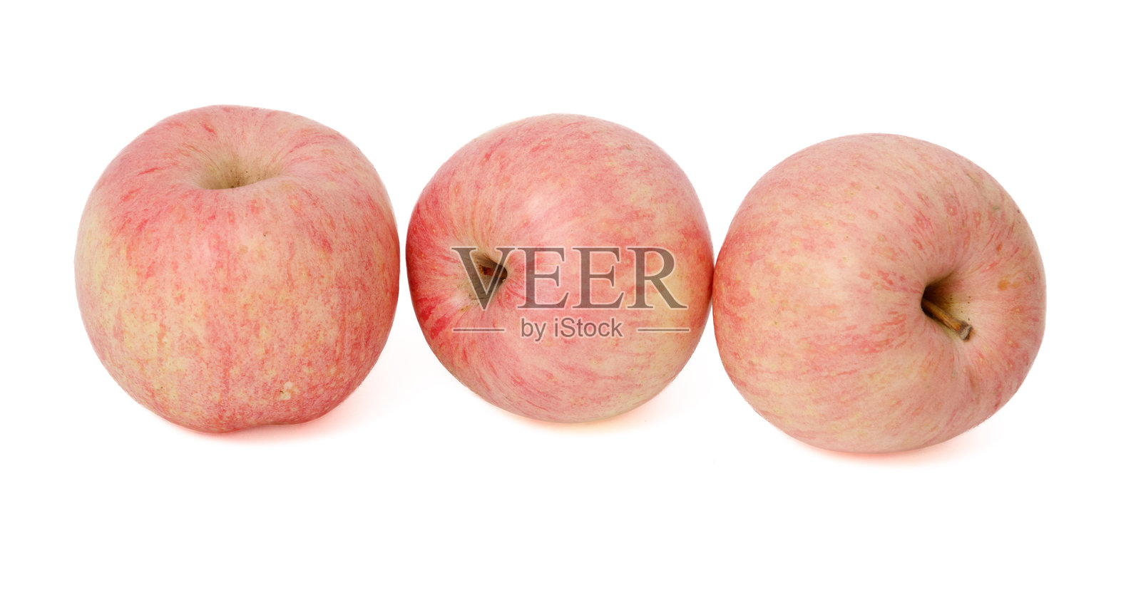 三只苹果排成一行，中间的苹果最大。照片摄影图片