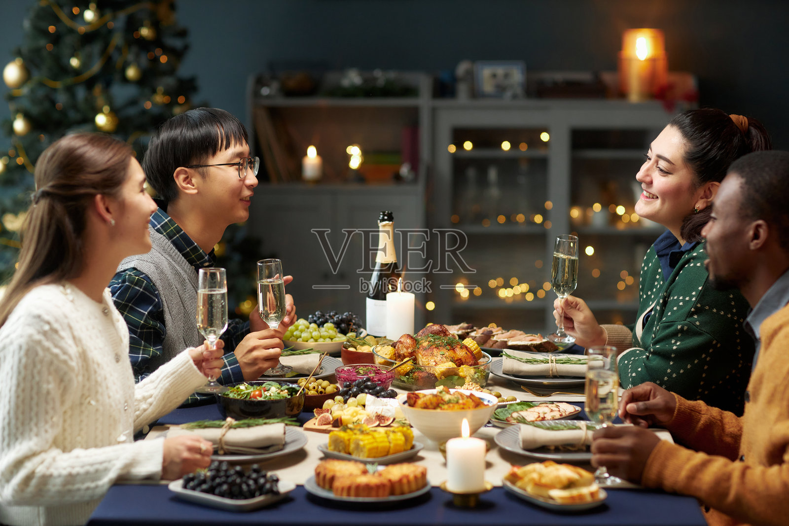 微笑的多民族人们在家中庆祝圣诞晚餐时聊天照片摄影图片