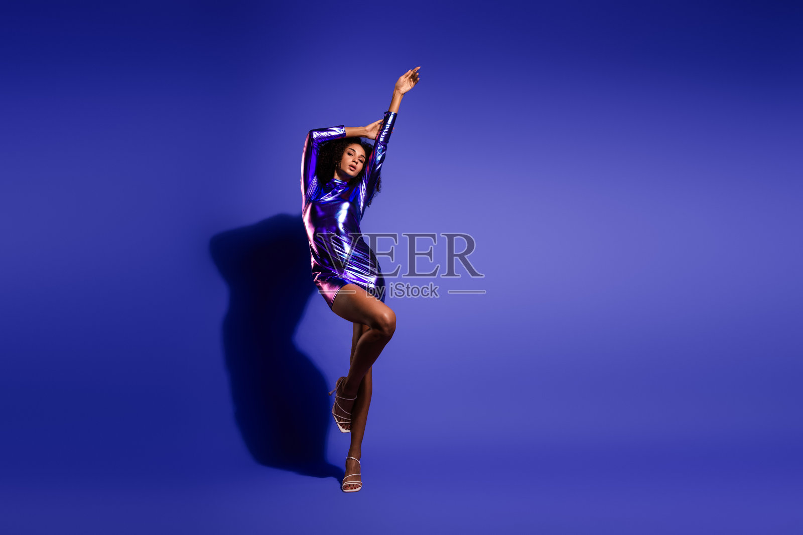 身穿华丽金属裙的时尚非洲女性在充满活力的紫色背景前摆出自信的姿势照片摄影图片