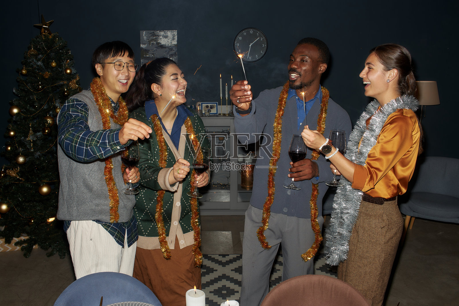 一群多元化的朋友在家庆祝圣诞节，手持烟花欢笑聊天照片摄影图片