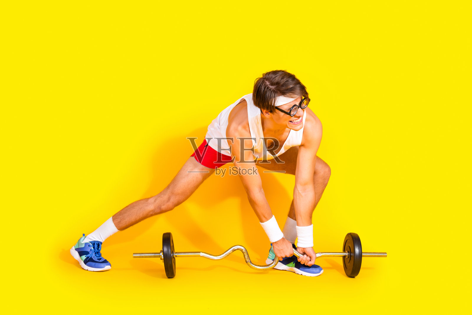 年轻运动员穿着色彩鲜艳的运动服在充满活力的黄色背景下举重，展现出对健身的热情和活力。照片摄影图片