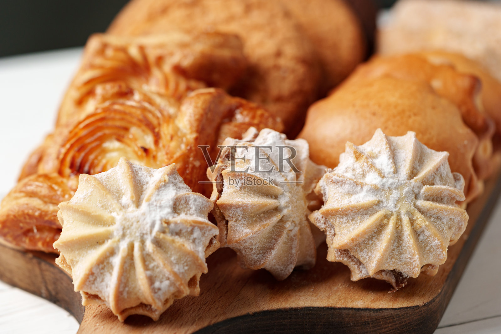 美味的烘焙食品组合展示在木板上，包含蛋白霜饼干和糕点，营造出温馨的面包店氛围照片摄影图片