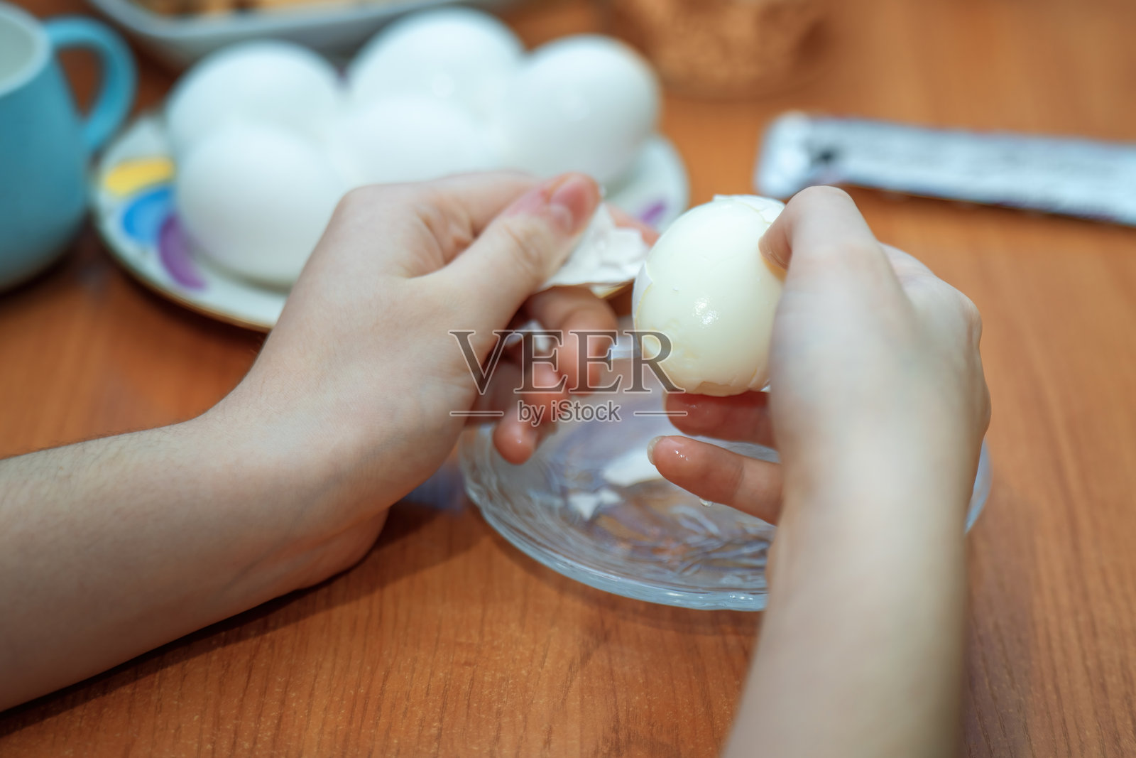 孩子的手在桌子上小心翼翼地清洗一个煮熟的白色鸡蛋，象征着纯真与发现。这一行为反映了好奇心和童年中简单任务的乐趣。照片摄影图片