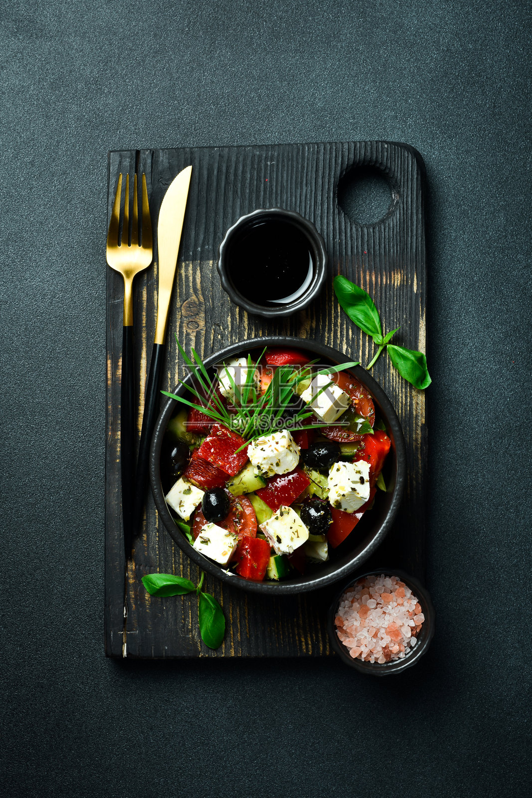 黑碗中的希腊沙拉配以羊奶酪。背景昏暗，特写镜头。照片摄影图片
