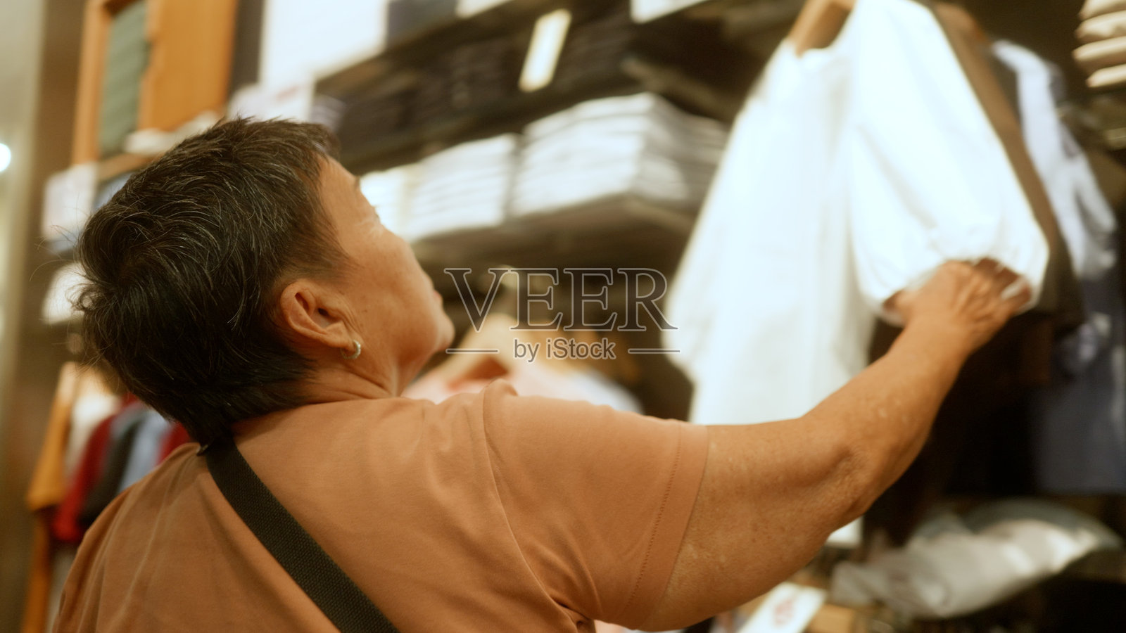 亚洲老年女性在购物并挑选衣服。照片摄影图片