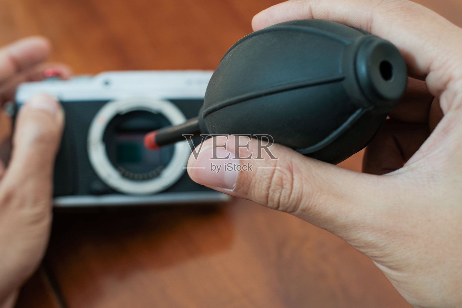 在木桌上用吹气球清洁相机传感器照片摄影图片