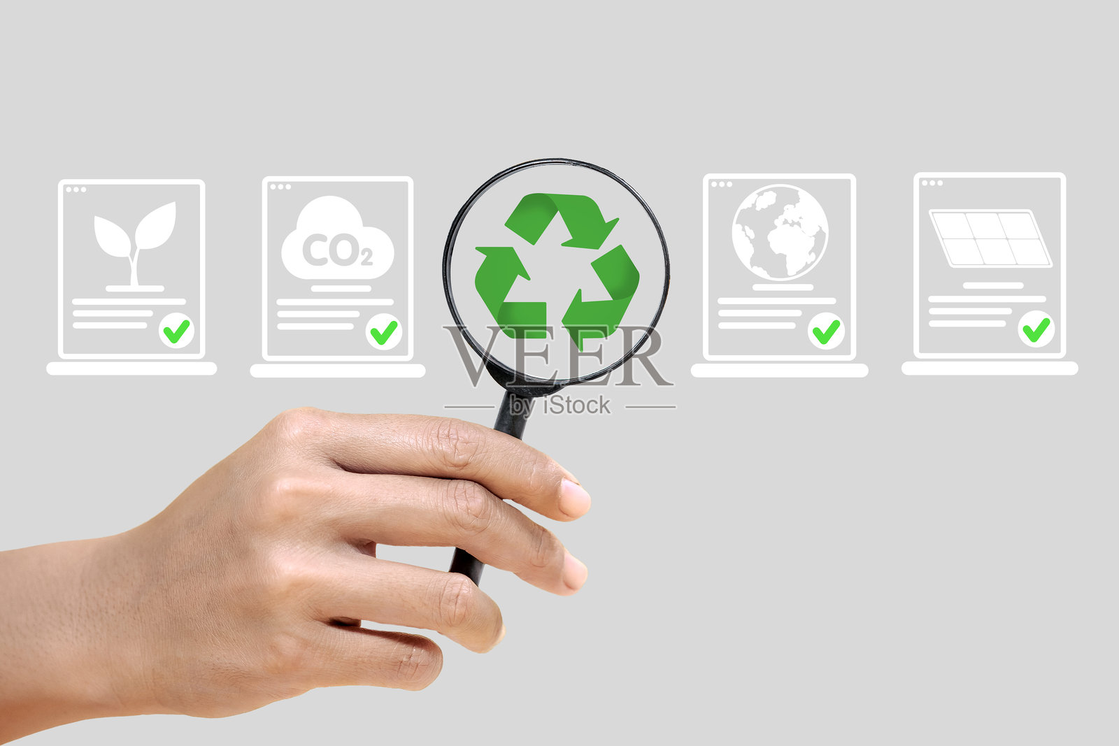 一只手握着放大镜，放大镜上有绿色回收标志照片摄影图片