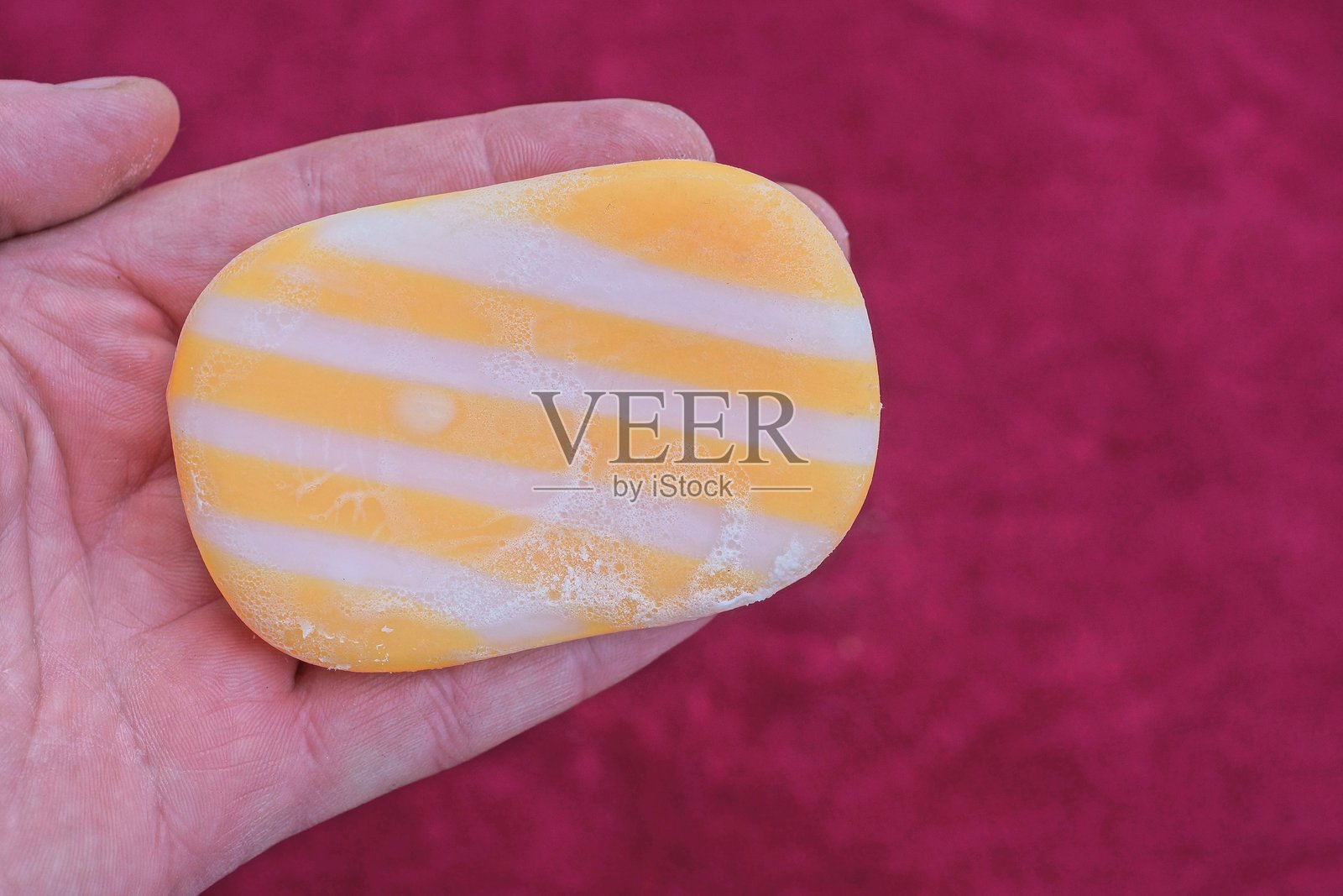 一块白色和黄色条纹的肥皂躺在手掌上照片摄影图片