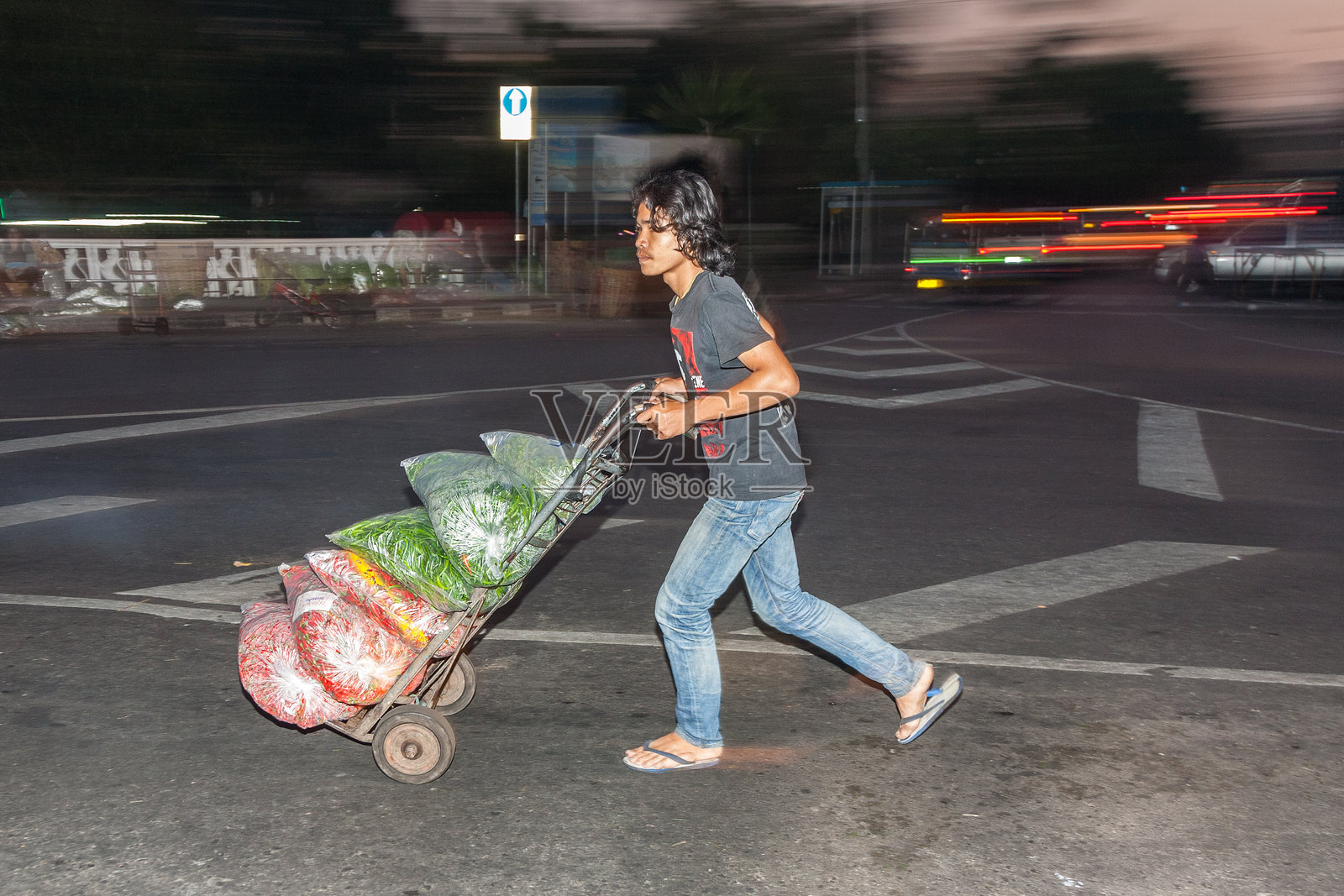 清晨，一名男子手推车上用塑料袋装着购买的鲜花。照片摄影图片