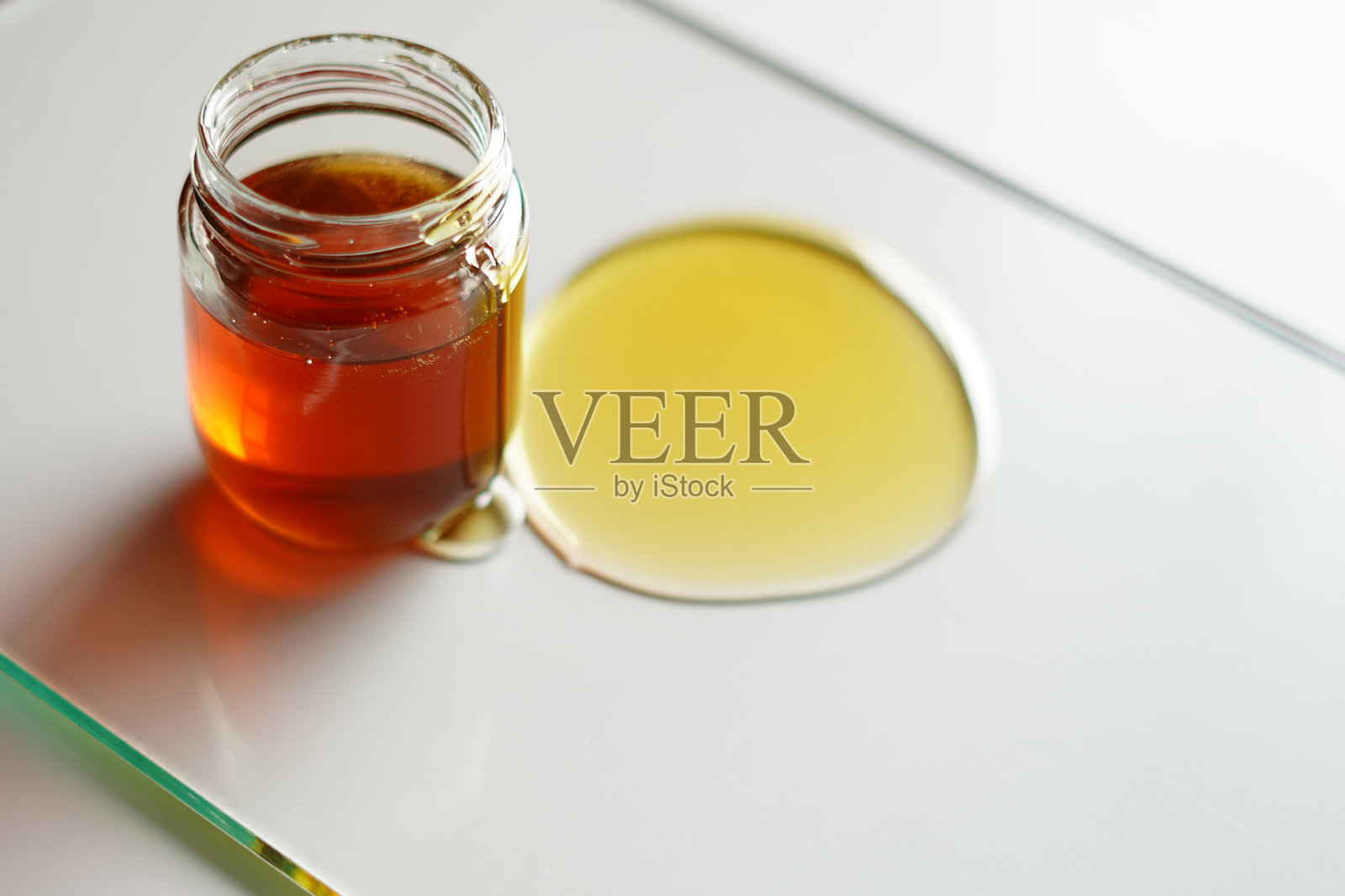 玻璃桌上的金色蜂蜜和玻璃罐。优质食品摄影照片摄影图片