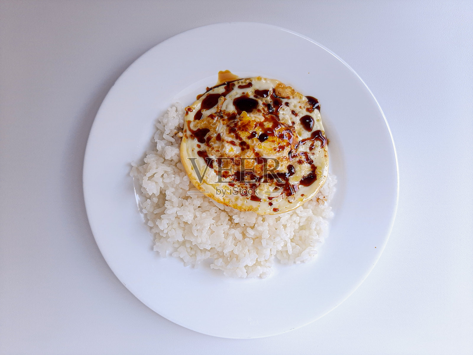 煎蛋或单面煎蛋，配白米饭和酱油，放在白色盘子里，背景为白色，留有文字空间。照片摄影图片