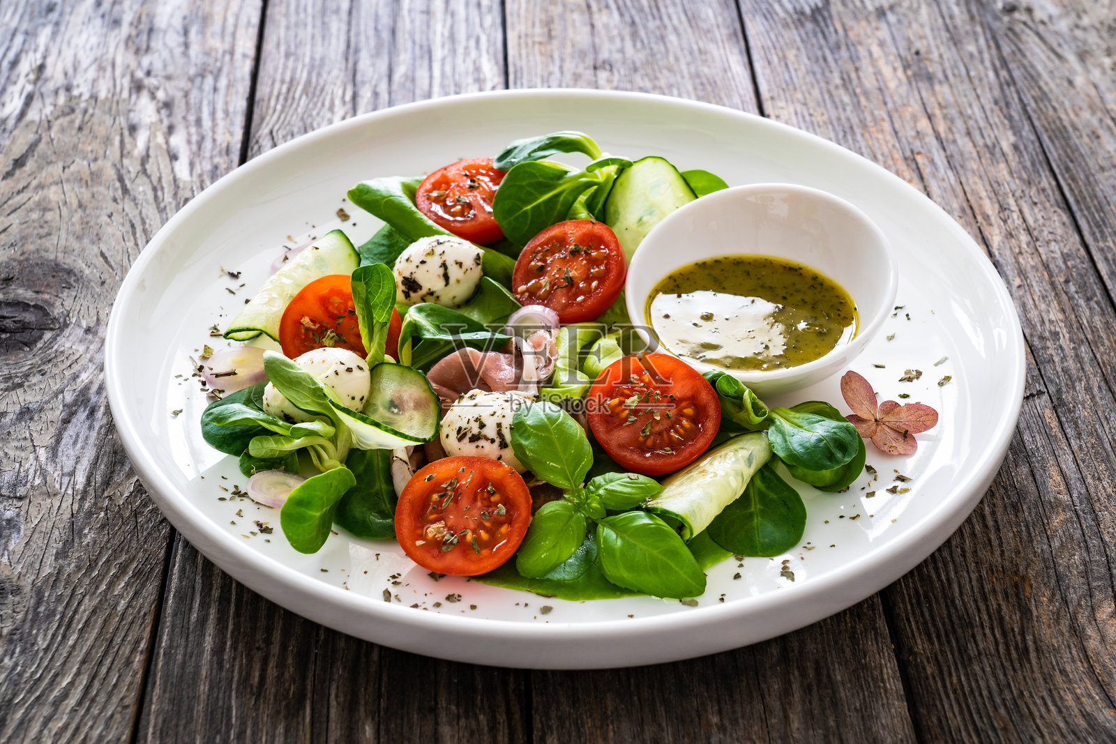 新鲜沙拉 - 帕尔马火腿、马苏里拉奶酪、黄瓜、西红柿和绿叶蔬菜放在木桌上照片摄影图片