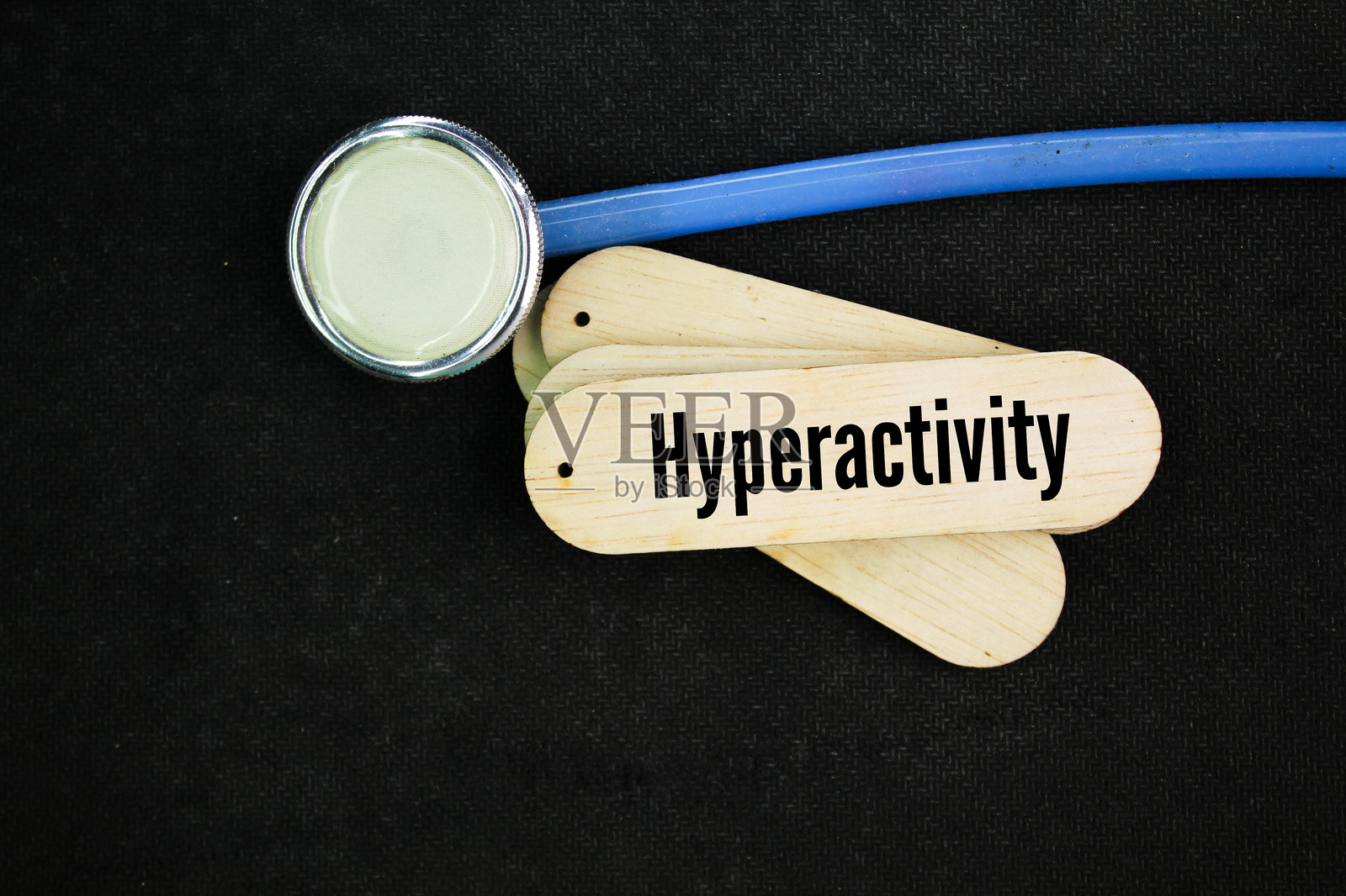 听诊器和带有“过度活跃”字样的棍子。过度活跃的状态。照片摄影图片