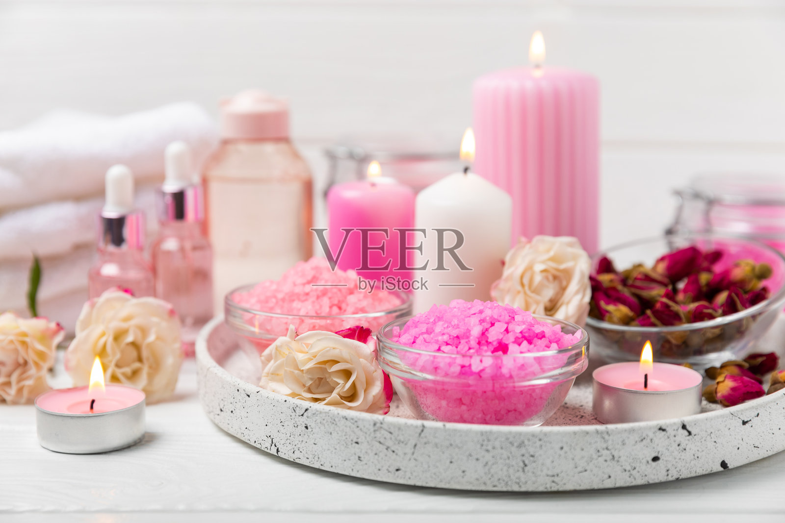 带有香气和玫瑰花的海盐浴，背景为纹理木材。粉色海盐。水疗护理。含草药和精油的天然盐。护肤概念。文本的中间留白。照片摄影图片