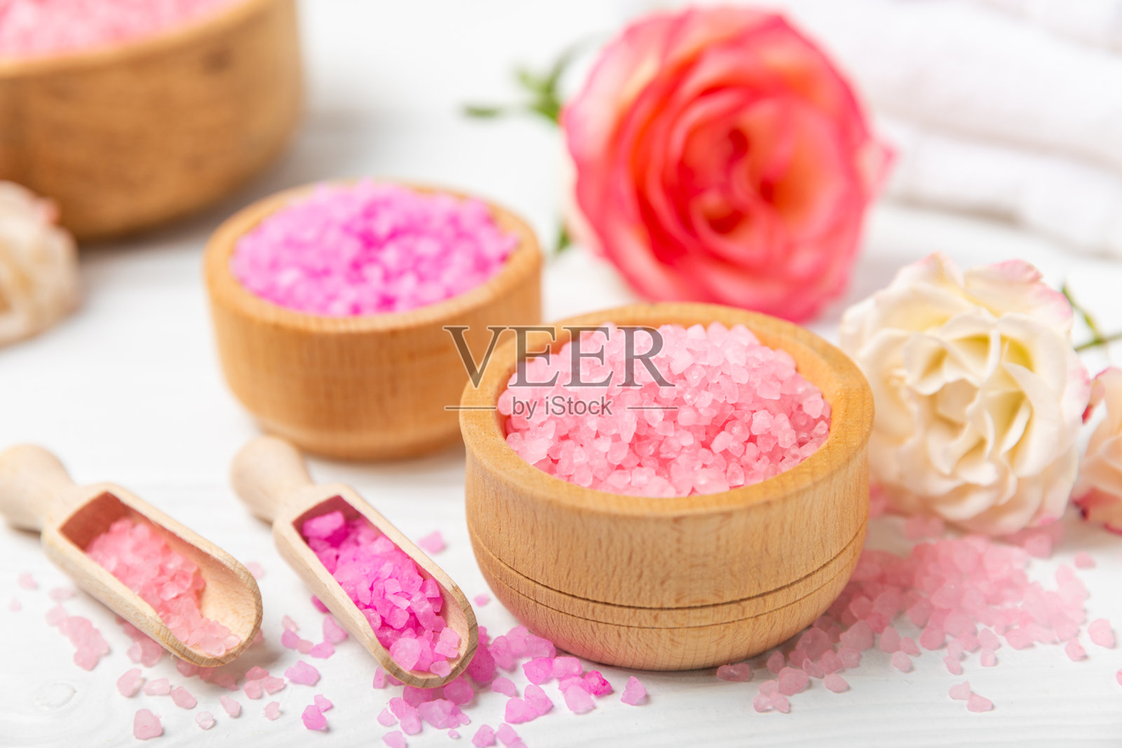 带有香气和玫瑰花的海盐浴，背景为纹理木材。粉色海盐。水疗护理。含草药和精油的天然盐。护肤概念。文本的中间留白。照片摄影图片