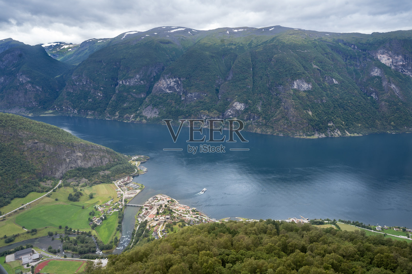 鸟瞰挪威奥尔朗斯旺根村，坐落在郁郁葱葱的绿地旁，俯瞰奥尔朗斯峡湾。四周被巍峨的山脉和戏剧性的多云天空环绕。照片摄影图片