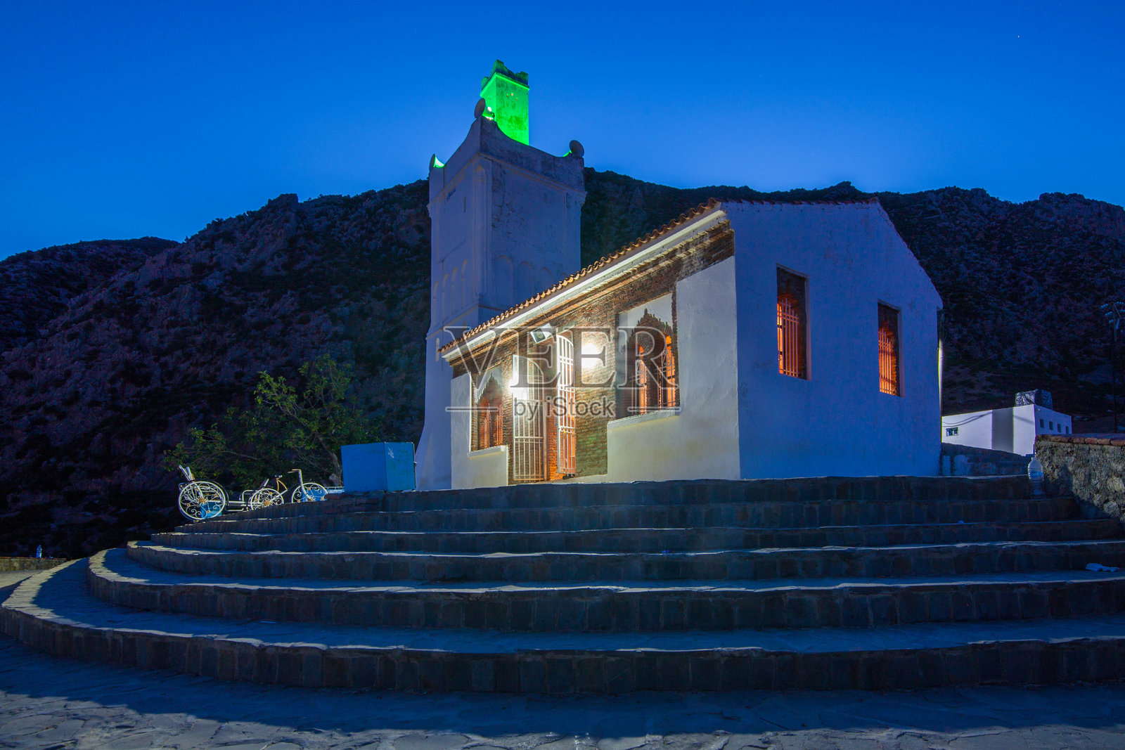 夜间照亮的清真寺，独特的塔楼，背景是黑暗的山脉和深蓝色的天空照片摄影图片