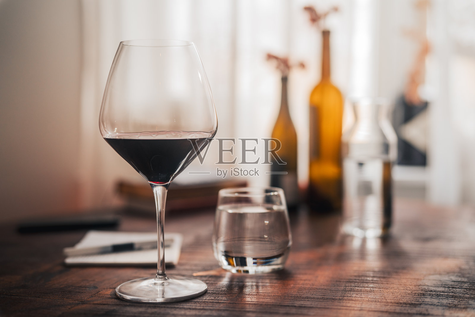 木桌上的红酒杯营造出温馨家居环境中的奢华感照片摄影图片