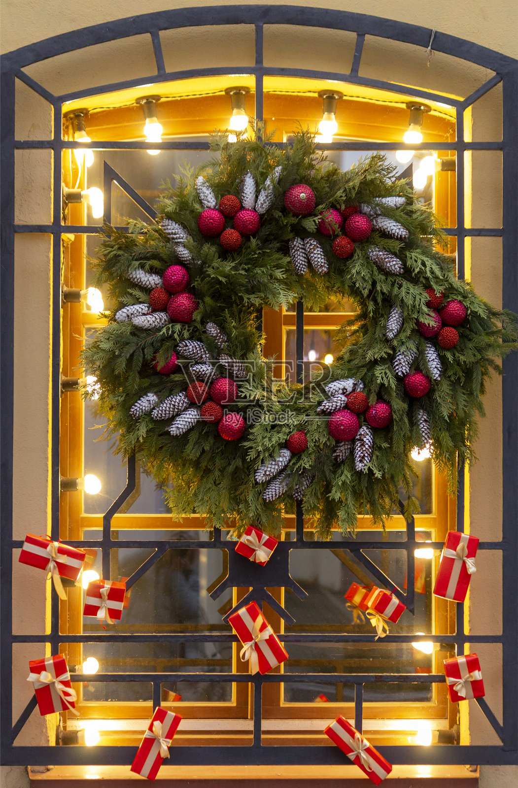 窗户装饰着圣诞节的装饰，有新年花环、球、松果和红色礼盒。竖版照片照片摄影图片