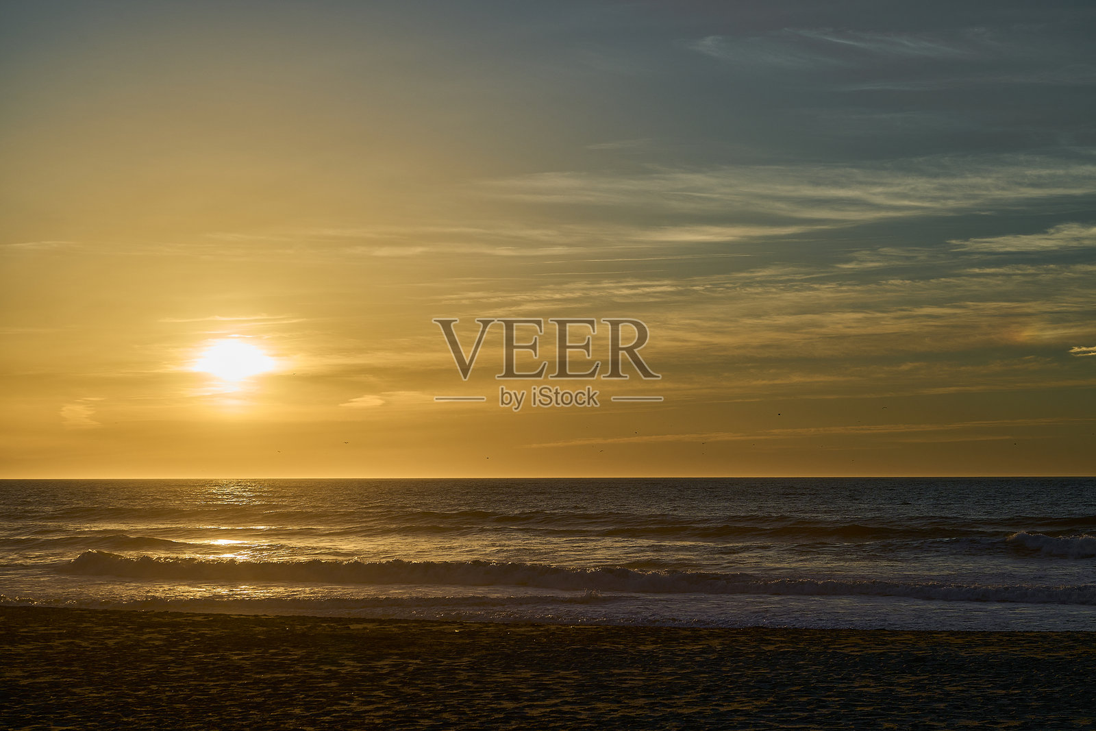 海滩上浪潮在浪漫日落时拍打岸边。照片摄影图片