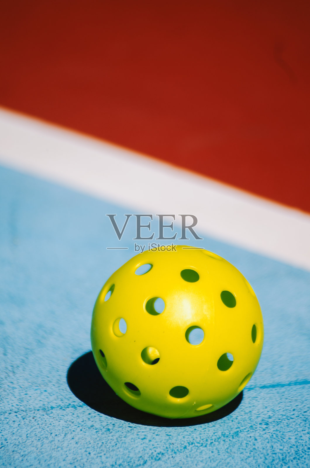 一颗孤独的皮克球在红蓝相间的球场上，新的球拍运动照片摄影图片